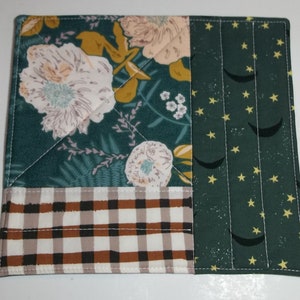 May include: A green fabric patchwork placemat with a floral pattern, a gingham pattern, and a pattern of stars and crescent moons.