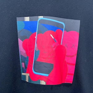 May include: A black sweatshirt featuring a graphic print of bright red cartoon figures with X-shaped eyes. A light blue rectangular frame resembling a smartphone screen overlays the figures, with one figure holding a small white paintbrush.