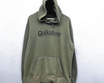 May include: Olive green Quiksilver hoodie with a drawstring hood and a kangaroo pocket. The Quiksilver logo is printed across the chest in black. The hoodie is made of a soft, comfortable material.