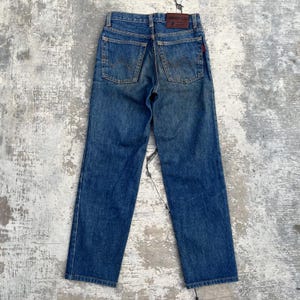 Pode incluir: Cal&ccedil;as de ganga azuis com um design cl&aacute;ssico de cinco bolsos. As cal&ccedil;as de ganga apresentam um corte de perna reto e uma lavagem desbotada, com um remendo de couro na cintura traseira. Os bolsos traseiros t&ecirc;m um design costurado distinto. Estilo vintage.