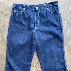 K&ouml;nnte beinhalten: Dunkelblaue Jeans aus Denim mit wei&szlig;en N&auml;hten. Die Jeans haben einen Knopfverschluss, Vordertaschen und Ges&auml;&szlig;taschen. Ein klassischer Stil, geeignet f&uuml;r den Alltag.