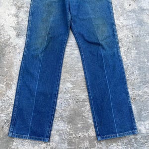 May include: Blue denim jeans with a classic straight leg cut. The jeans have a faded appearance and feature a traditional five-pocket design. The pants are made of durable denim material.