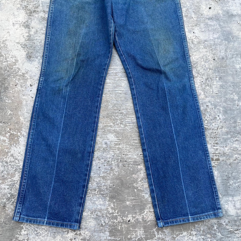 May include: Blue denim jeans with a classic straight leg cut. The jeans have a faded appearance and feature a traditional five-pocket design. The pants are made of durable denim material.