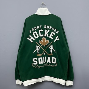 May include: Green hockey sweatshirt with white collar and cuffs. The back features the words "FRONT RUNNER HOCKEY SQUAD" in white, with a maple leaf and crossed hockey sticks. The sweatshirt has a relaxed fit.