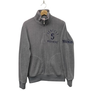 May include: Gray Seattle Mariners quarter-zip sweatshirt with the team logo and text on the chest and sleeve. The sweatshirt has a high collar, a front pocket, and ribbed cuffs and hem.