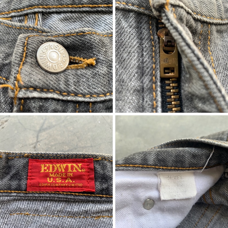 May include: Close-up of gray denim jeans with visible details. Features include a button with "EDWIN" text, a zipper, and a red tag with "EDWIN MADE IN U.S.A." text. The stitching is in a contrasting yellow color.