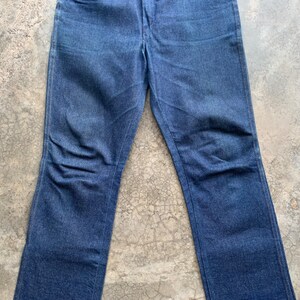 K&ouml;nnte beinhalten: Eine blaue Jeanshose. Die Jeans hat ein klassisches F&uuml;nf-Taschen-Design, einen Knopf- und Rei&szlig;verschluss und eine gerade Beinpassform. Der Denim hat eine mittelblaue Waschung mit dezenten Ausbleichungen und Knitterfalten.