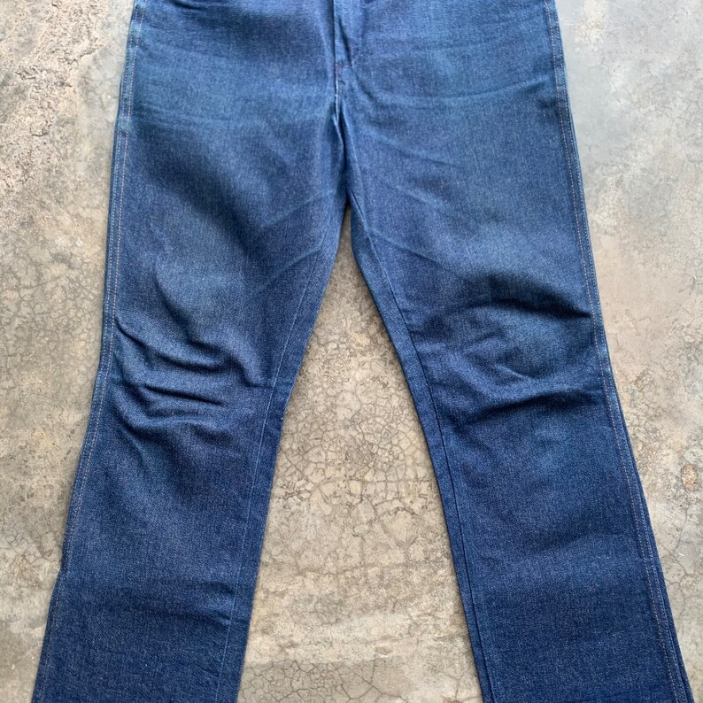 K&ouml;nnte beinhalten: Eine blaue Jeanshose. Die Jeans hat ein klassisches F&uuml;nf-Taschen-Design, einen Knopf- und Rei&szlig;verschluss und eine gerade Beinpassform. Der Denim hat eine mittelblaue Waschung mit dezenten Ausbleichungen und Knitterfalten.