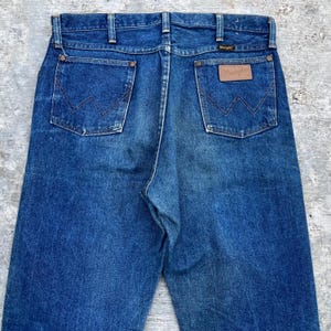 Pode incluir: Cal&ccedil;as de ganga azuis com o log&oacute;tipo Wrangler no bolso traseiro. As cal&ccedil;as de ganga t&ecirc;m um design cl&aacute;ssico de cinco bolsos e um corte reto. A ganga tem um aspeto desbotado.