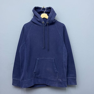 Könnte beinhalten: Ein marineblauer Kapuzenpullover mit Kordelzug und Kängurutasche. Der Sweatshirt besteht aus einem weichen, bequemen Material und hängt an einem Holzbügel.