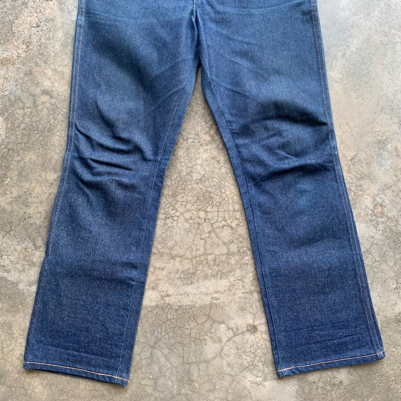 K&ouml;nnte beinhalten: Dunkelblaue Jeans aus Denim mit klassischer gerader Beinpassform. Die Jeans haben ein traditionelles F&uuml;nf-Taschen-Design und einen Knopf- und Rei&szlig;verschluss. Die N&auml;hte sind in einer kontrastierenden Beiget&ouml;nung gehalten.