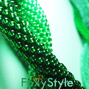 May include: Close-up of a green beaded necklace with a gradient of darker green beads. The necklace is made of small, round beads that are tightly woven together.