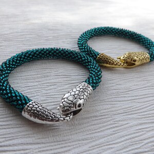 Puede incluir: Dos pulseras de serpiente de cuentas con cierres de cabeza de serpiente plateados y dorados. Las pulseras son de color azul verdoso y est&aacute;n hechas de cuentas peque&ntilde;as.