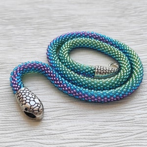 May include: A beaded snake necklace with a silver snake head charm. The beads are iridescent and change color from green to blue to purple.