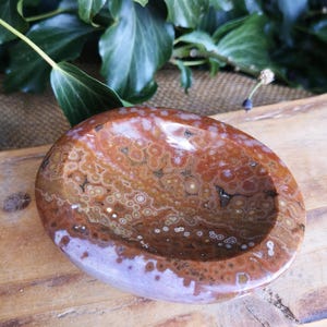 May include: A brown and white agate bowl with a swirling pattern. The bowl is oval shaped and has a smooth, polished finish.