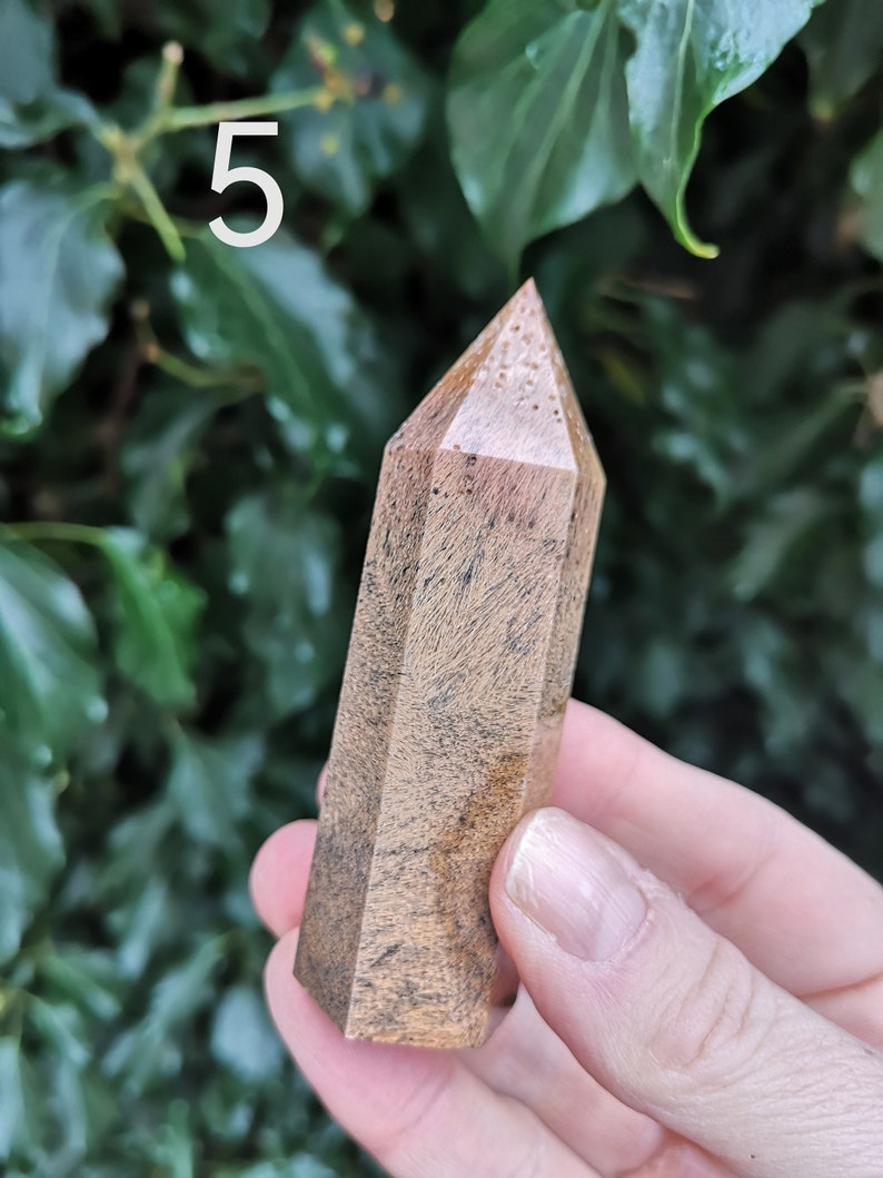 Puede incluir: Una punta de cristal de madera marr&oacute;n y negro con una punta puntiaguda. El cristal mide aproximadamente 12,7 cm de largo y tiene un aspecto natural y org&aacute;nico.
