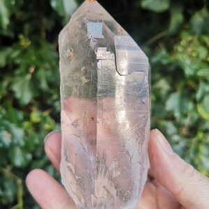 May include: A large, clear quartz crystal with a natural point and a double termination. The crystal has a cloudy, milky appearance and is approximately 12.5 cm tall.