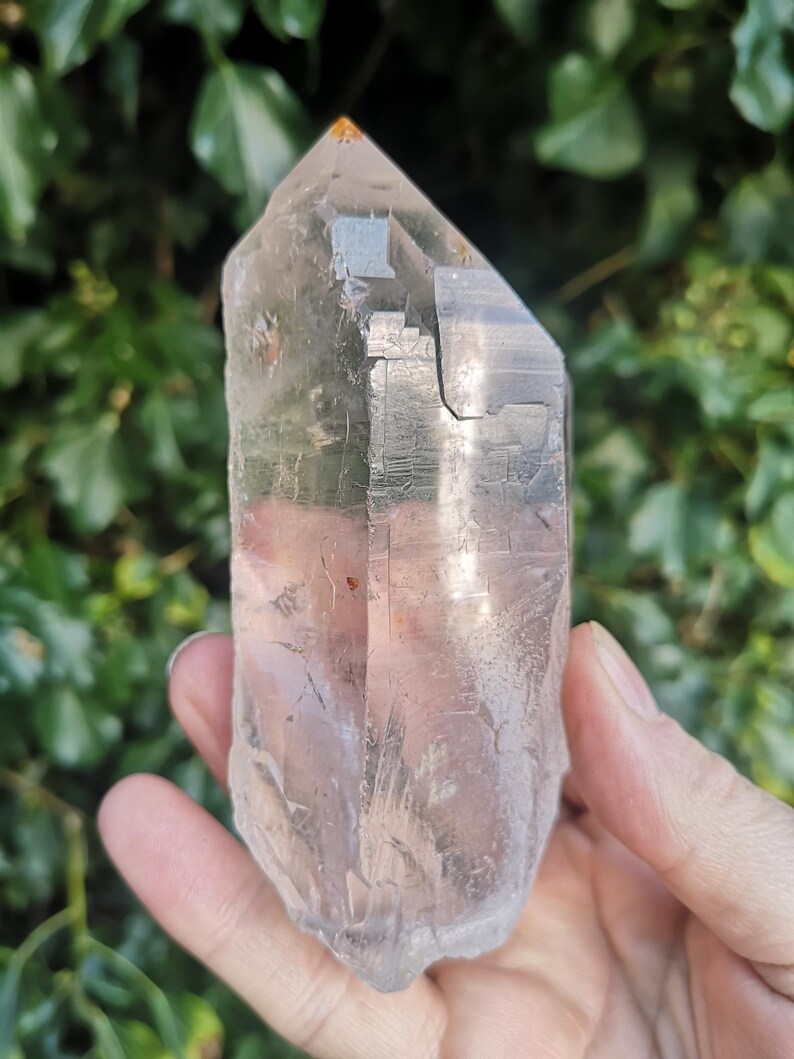 May include: A large, clear quartz crystal with a natural point and a double termination. The crystal has a cloudy, milky appearance and is approximately 12.5 cm tall.