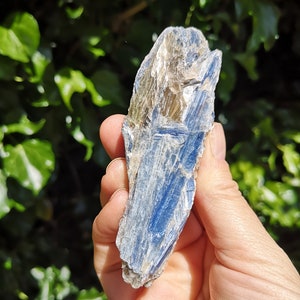 K&ouml;nnte beinhalten: Ein blauer Kyanit-Kristall mit silbernem Schimmer. Der Kristall ist rau und hat ein nat&uuml;rliches, rohes Aussehen.