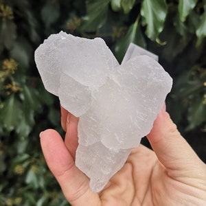 May include: A large, white, translucent crystal cluster with a rough, textured surface. The crystal is shaped like a mountain and has many facets.