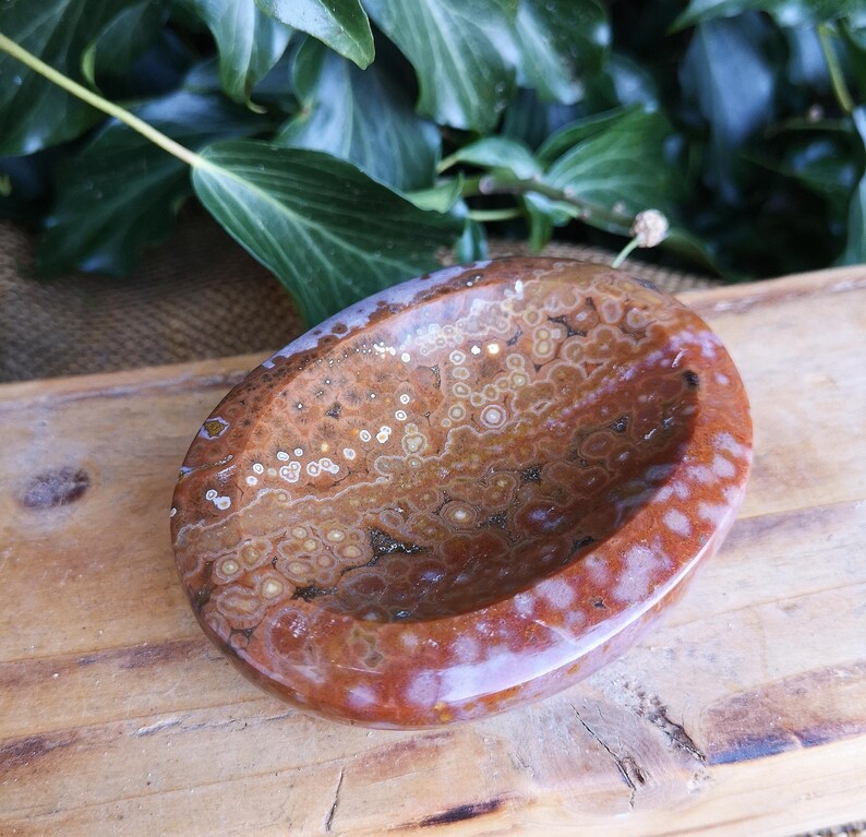 May include: A brown and white agate bowl with a swirling pattern. The bowl is oval shaped and has a smooth, polished finish.