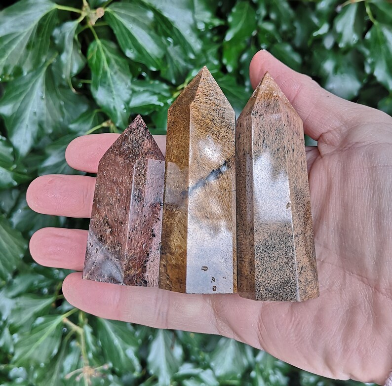 Puede incluir: Tres varitas de cristal pulidas, puntiagudas, con rayas marrones y blancas. Las varitas est&aacute;n dispuestas en fila, con la varita m&aacute;s grande en el centro.