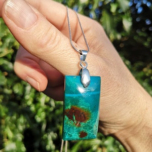 Pu&ograve; includere: Collana con pendente rettangolare in pietra preziosa turchese e marrone. La catena &egrave; d'argento. I colori e i motivi del pendente creano un contrasto sorprendente, rendendolo un gioiello unico.