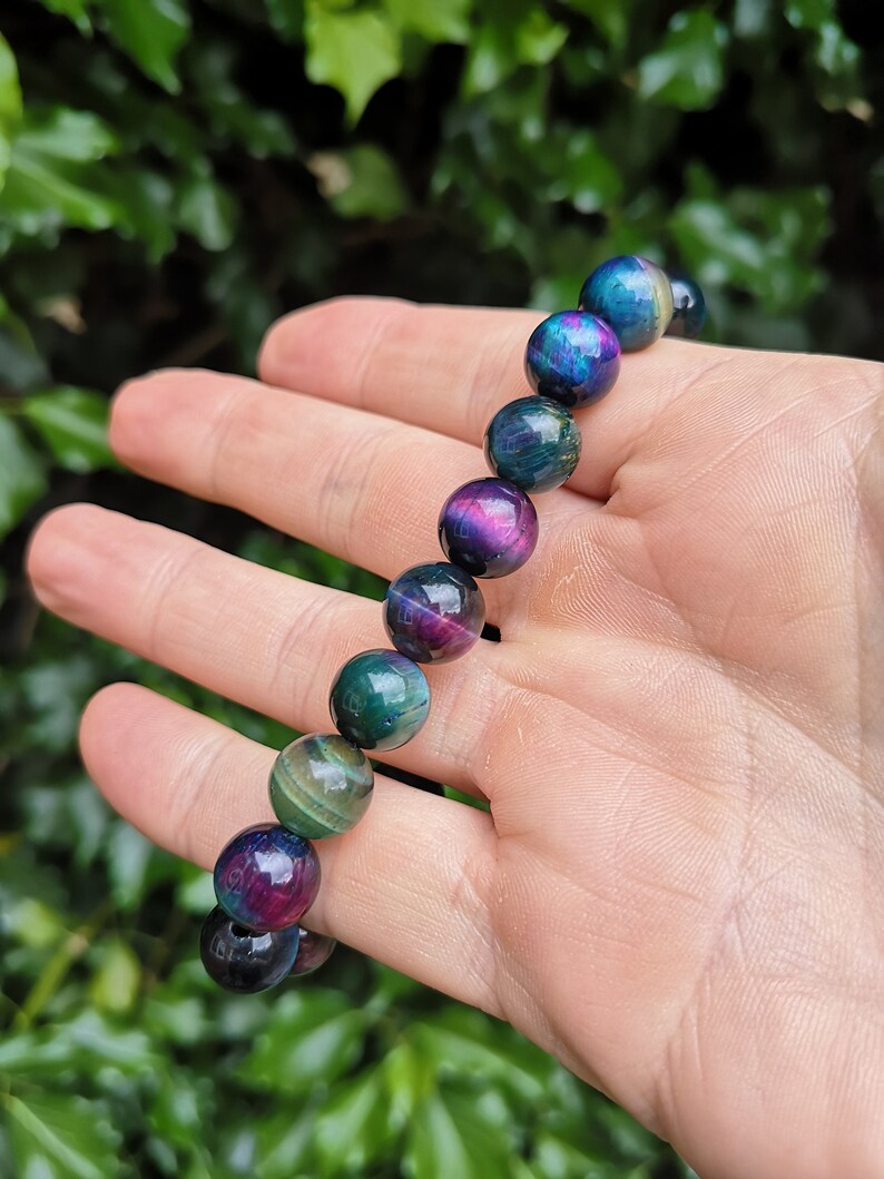 May include: A bracelet made of iridescent tiger's eye beads. The beads are round and have a mix of green, blue, and purple colors.