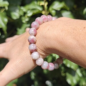 May include: A stretch bracelet composed of round, polished beads in varying shades of pink, white, and translucent rose. The beads feature natural marbling and internal inclusions, creating a unique pattern on each stone within the circular design.