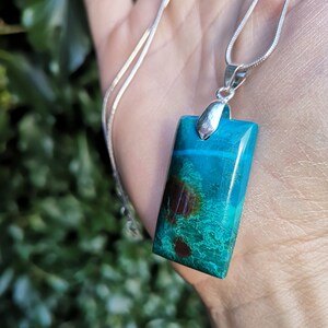 Pu&ograve; includere: Collana con pendente rettangolare turchese con inclusioni marroni e verdi. La catena &egrave; argentata. Il pendente &egrave; rettangolare e ha un'attaccatura argentata.