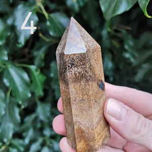 Puede incluir: Una punta de cristal de madera marr&oacute;n oscuro con un acabado liso y pulido. La punta tiene forma de pir&aacute;mide con una parte superior plana y seis lados.