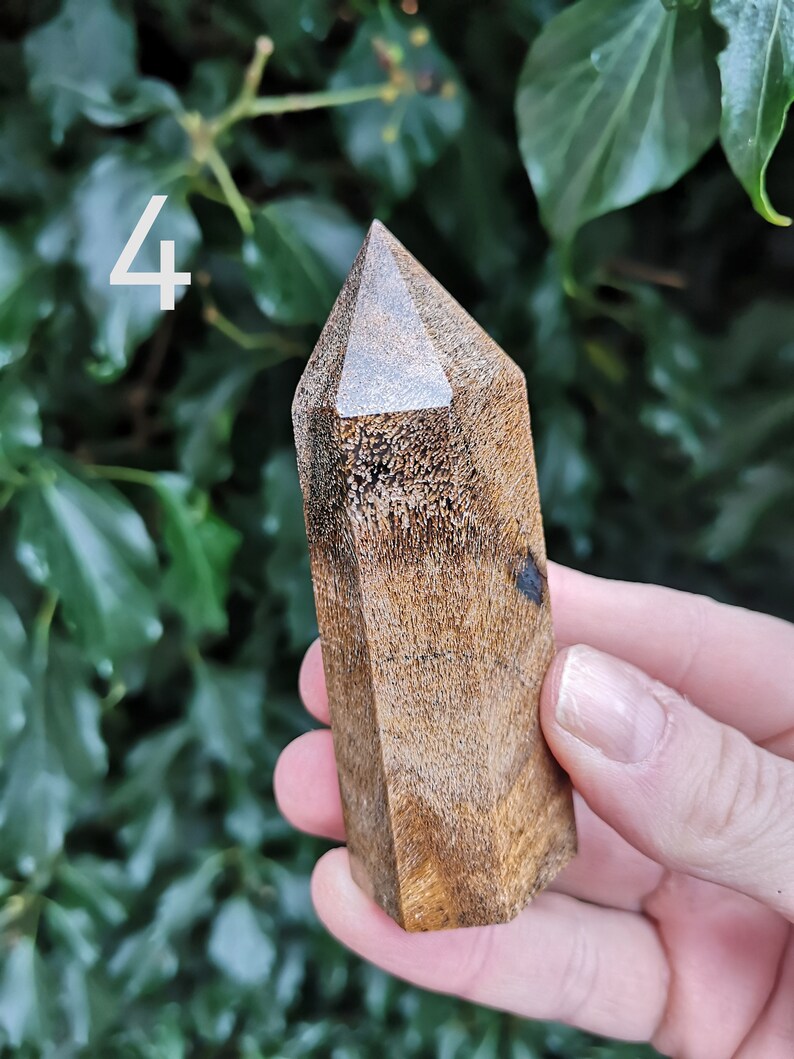 Puede incluir: Una punta de cristal de madera marr&oacute;n oscuro con un acabado liso y pulido. La punta tiene forma de pir&aacute;mide con una parte superior plana y seis lados.