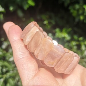 May include: A sunstone bracelet with a light brown color and a shimmery finish. The bracelet is made of rectangular beads.
