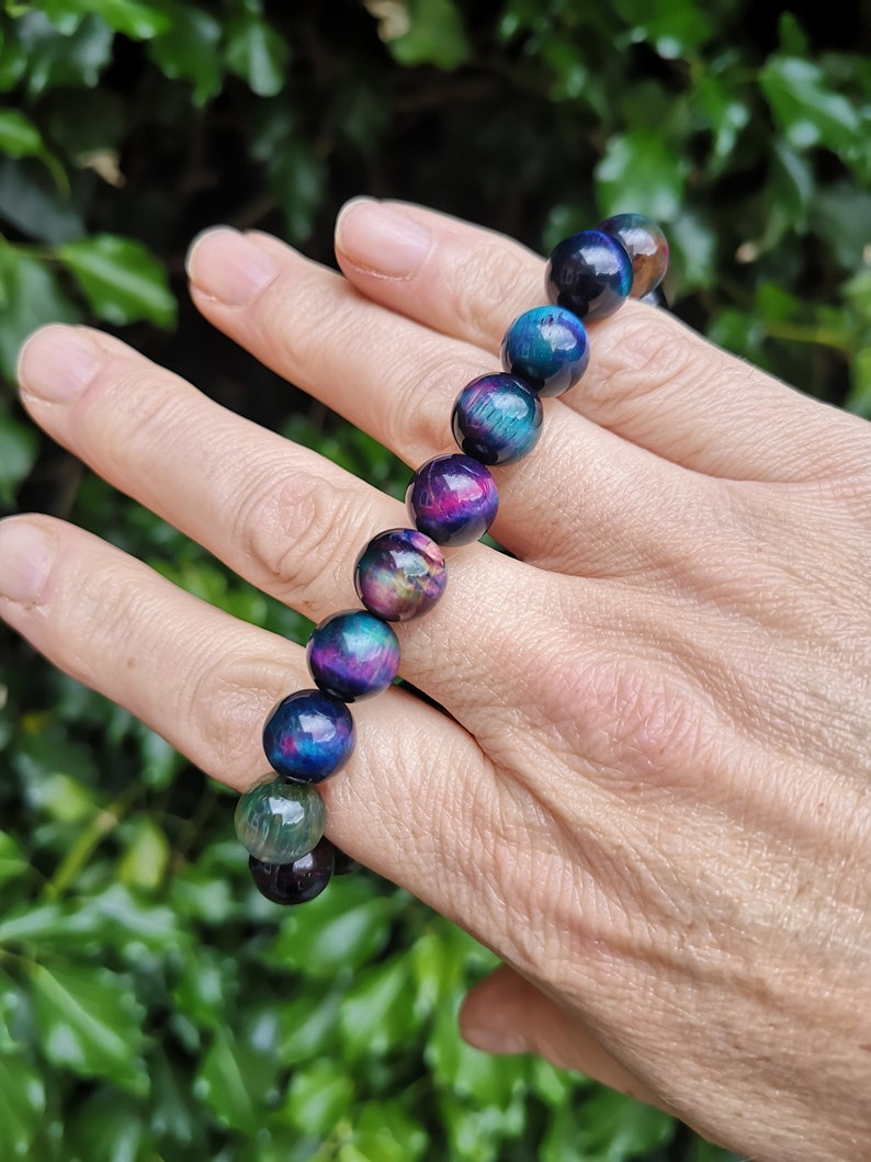 May include: A bracelet made of iridescent tiger's eye beads in shades of blue, green, and purple. The beads are round and have a smooth, polished finish.