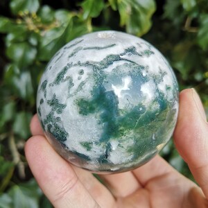 May include: Green and white agate sphere with swirling patterns. The sphere is polished and smooth.