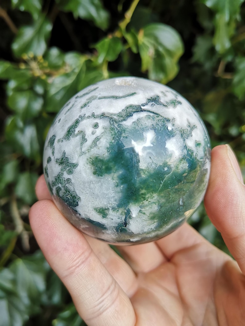 May include: Green and white agate sphere with swirling patterns. The sphere is polished and smooth.