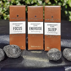 May include: Three brown aromatherapy blend boxes labelled "Focus", "Energise", and "Sleep". Each box has a white label with black text. The boxes are accompanied by four dark grey stones.