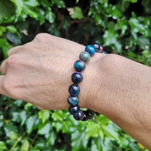 May include: A beaded bracelet with dark blue, green, and red beads. The bracelet is made of natural stone and has a polished finish.
