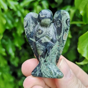 May include: Green and black patterned stone angel figurine. The angel is carved in a standing pose with wings outstretched.