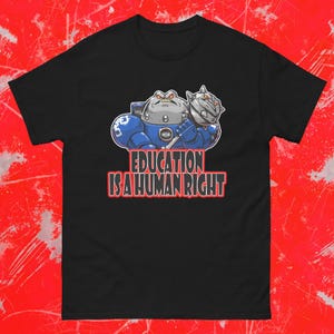 May include: Black t-shirt featuring a cartoon illustration of a robot-like figure in blue armor holding a spiked mace. The text "EDUCATION IS A HUMAN RIGHT" is displayed in red and white below the illustration.