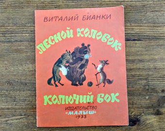 May include: A red book cover with the title "Лесной колобок" in green letters. The book is illustrated with a wolf, a bear, and a fox. The text "Колючий бок" is also in green letters. The book is published by "Малыш" in 1988.