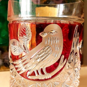 May include: A clear glass tumbler with a cut glass design. The tumbler is filled with a red liquid and features a silver etched design of a bird on a branch.