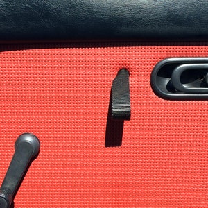 May include: Red car door interior with a black door handle and a black pull strap.