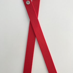 May include: Two red fabric straps with silver metal eyelets at each end.