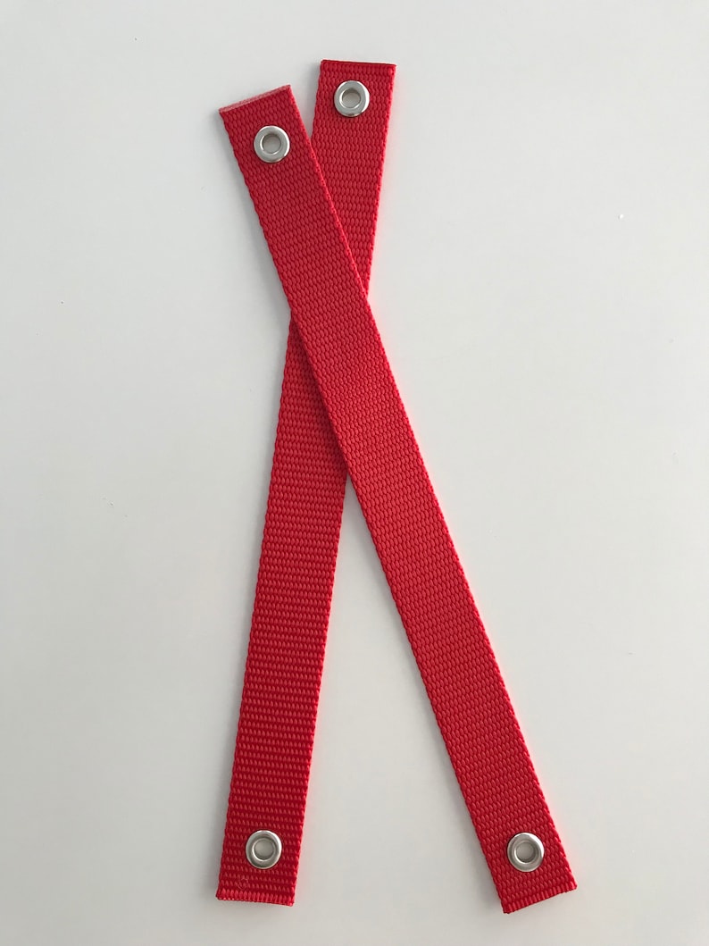 May include: Two red fabric straps with silver metal eyelets at each end.