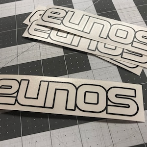 May include: A set of four white vinyl stickers with black outlines that read "Eunos".