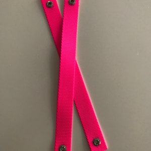 May include: Two pink fabric straps with metal eyelets at each end.