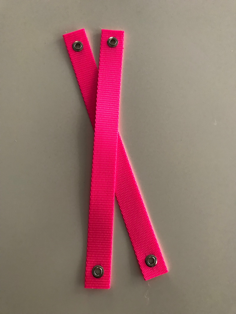 May include: Two pink fabric straps with metal eyelets at each end.