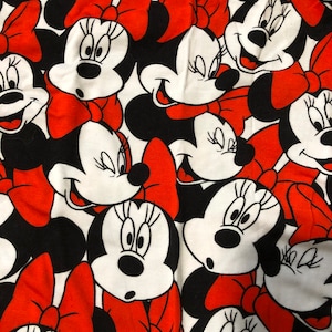 Puede incluir: Una tela blanca con un patr&oacute;n repetido de lazos rojos y caras de dibujos animados en blanco y negro de Minnie Mouse.