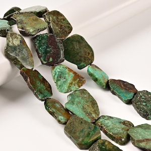 May include: A strand of irregular, flat, slab-shaped beads featuring a mottled mix of deep forest green, turquoise, and earthy brown tones. Each bead displays a unique, rough-hewn texture with natural color variations and visible mineral inclusions.